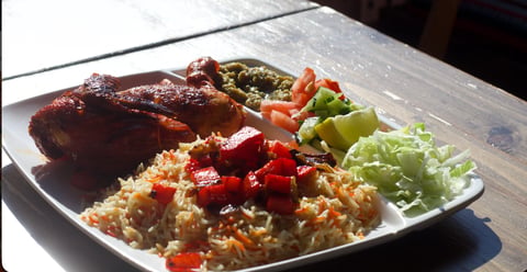 Plated meal with glazed meat, fried rice with red peppers, and fresh vegetable medley on white plate